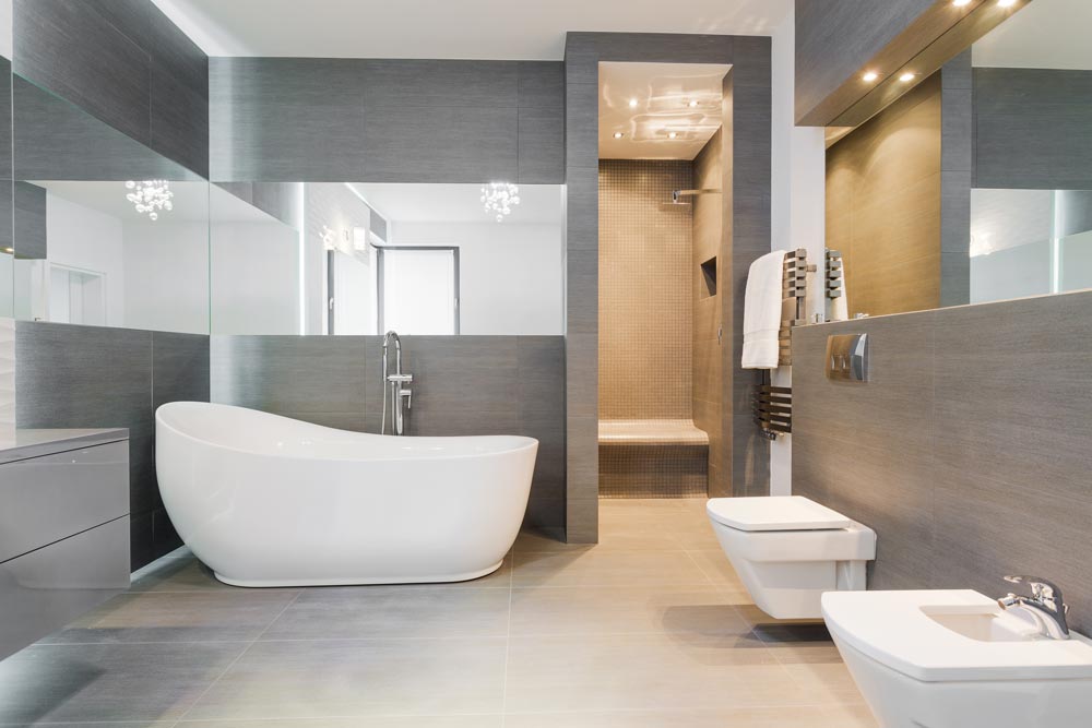 Ett nyrenoverat grått badrum med ett vitt badkar