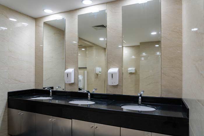 Ett modernt badrum med stora speglar och tvålpumpar på väggen